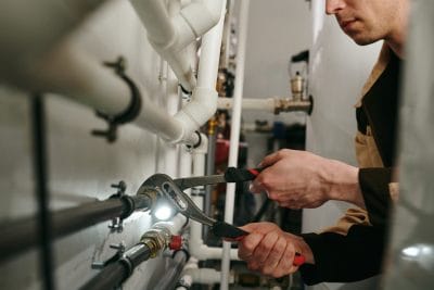 Technician inspecting commercial plumbing pipes in Moreno Valley