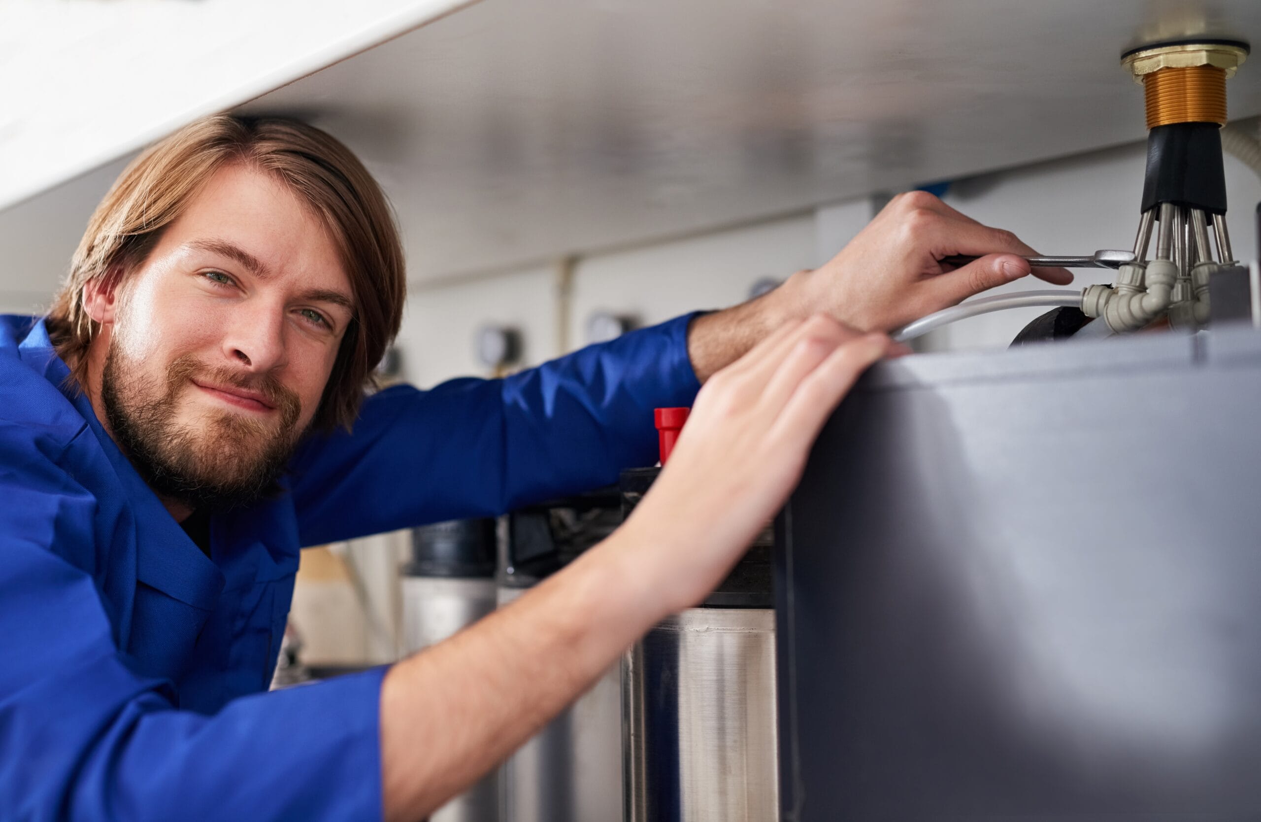 Technician servicing a residential water heater tank in Moreno Valley